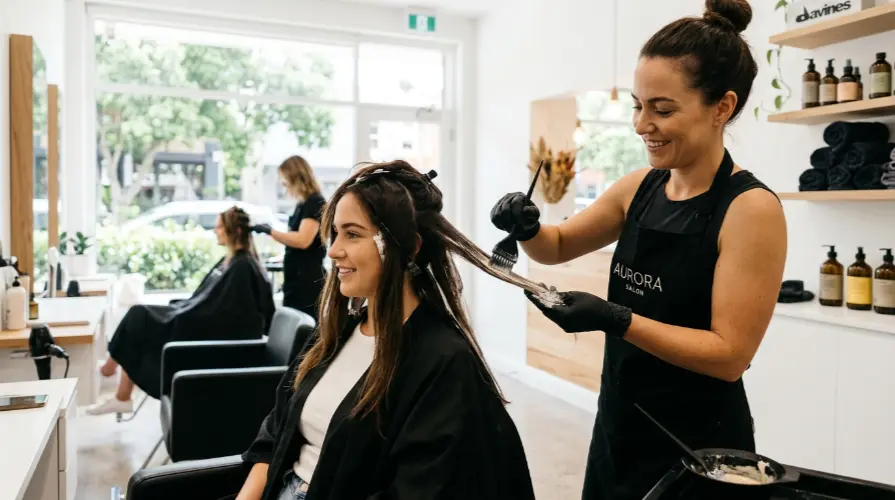 Professional hair colourist applying balayage highlights at Incredible Hair & Beauty salon in Liverpool NSW